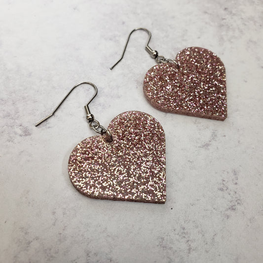 Heart shaped rose gold tone glitter acrylic earrings on stainless steel earring wires.