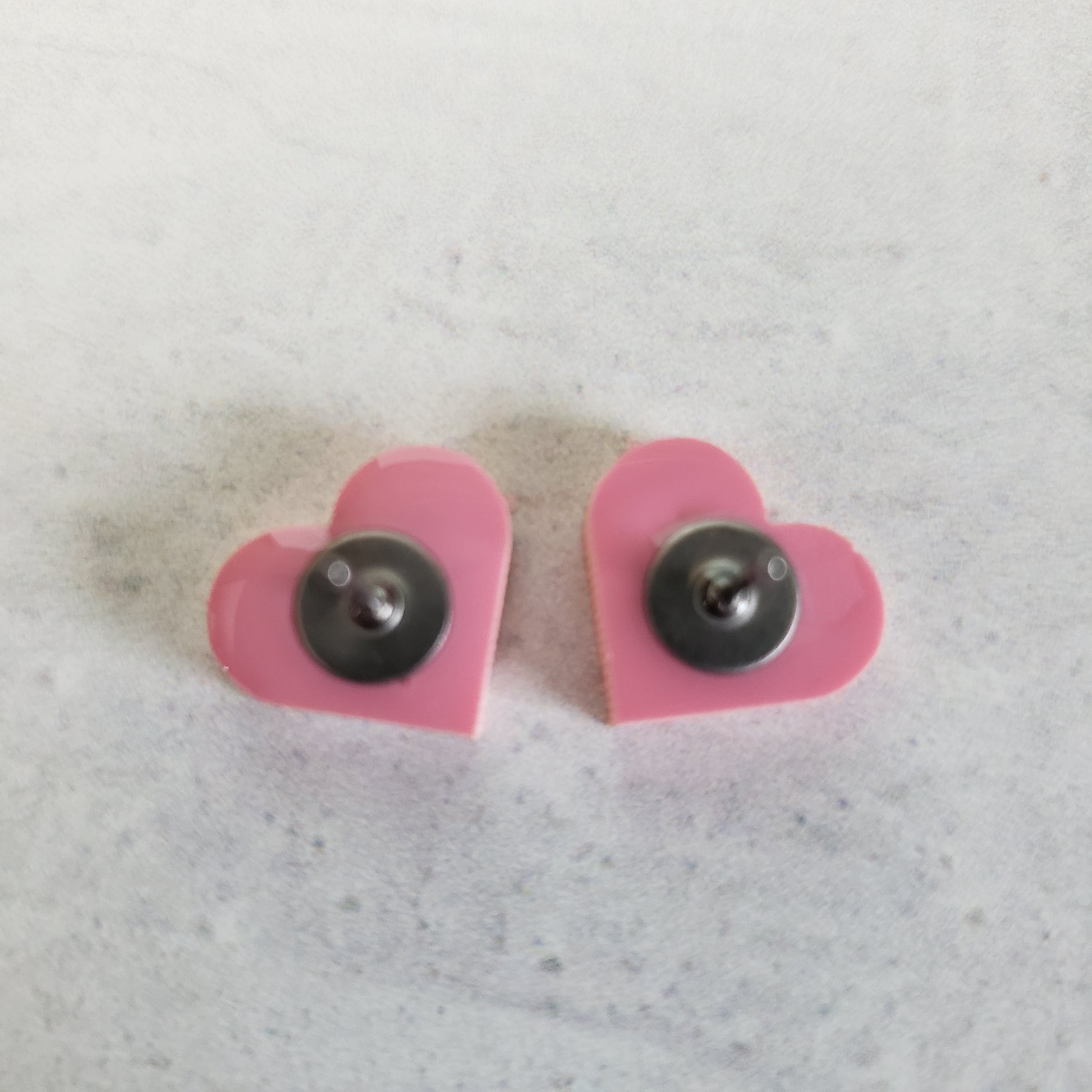 Backside of matte pink pastel heart shaped stud earrings.