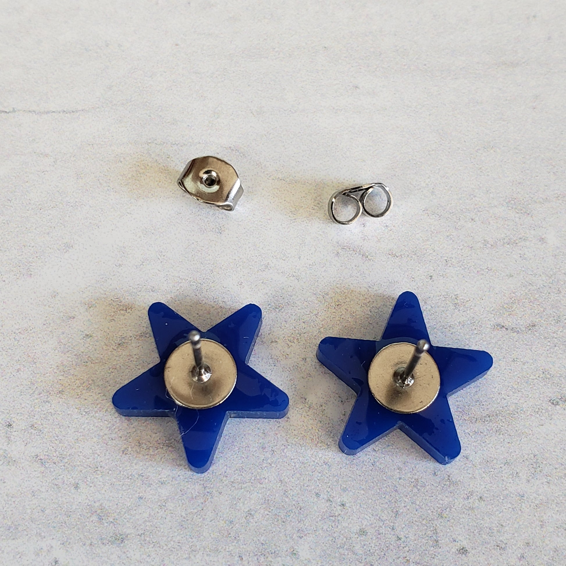 Backside of navy blue star stud earrings showing posts