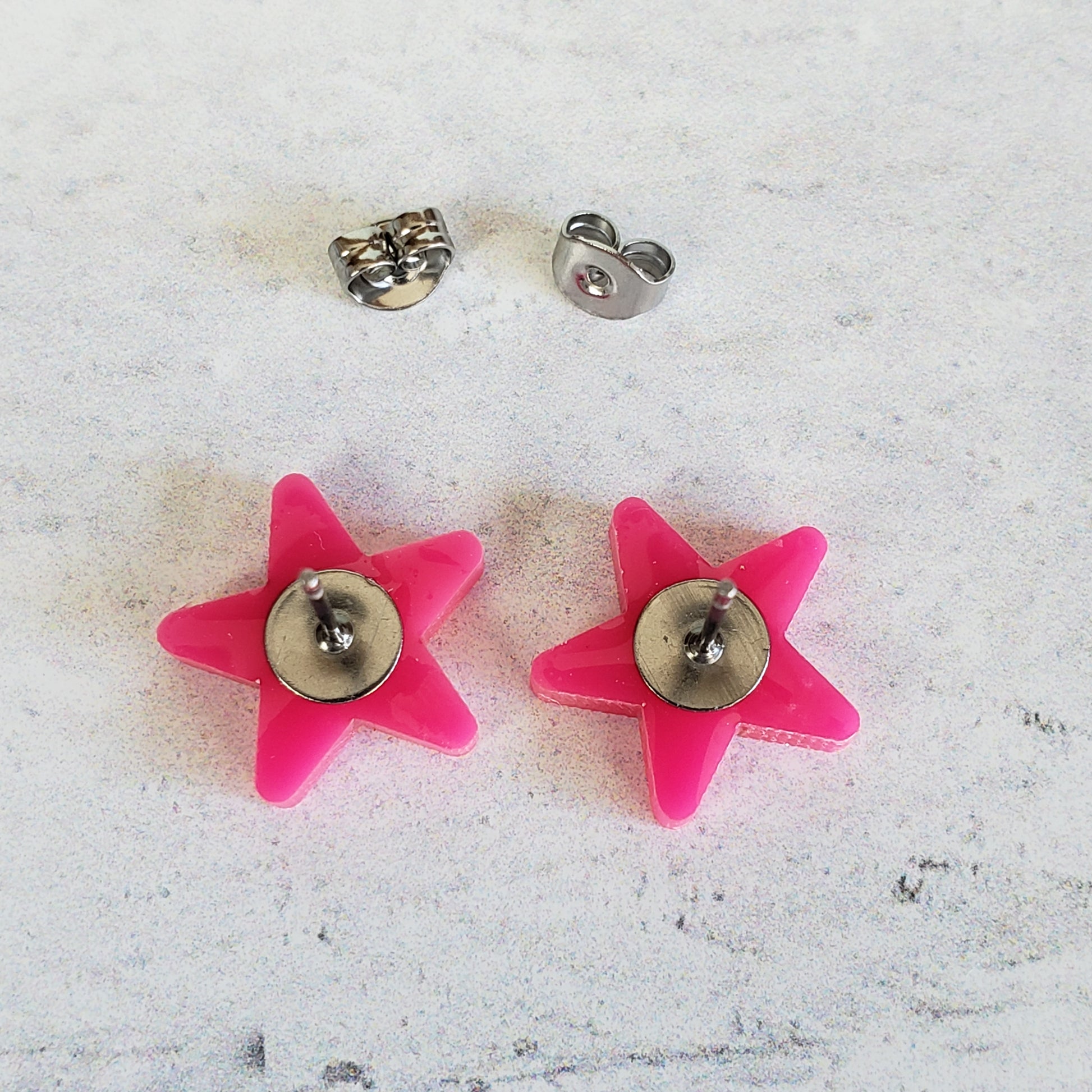 Backside of hot pink star stud earrings showing posts
