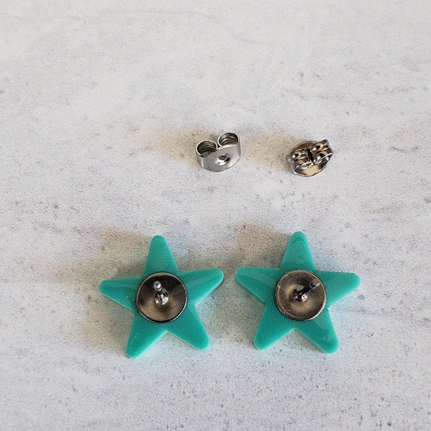 Backside of matte mint green star stud earrings showing posts