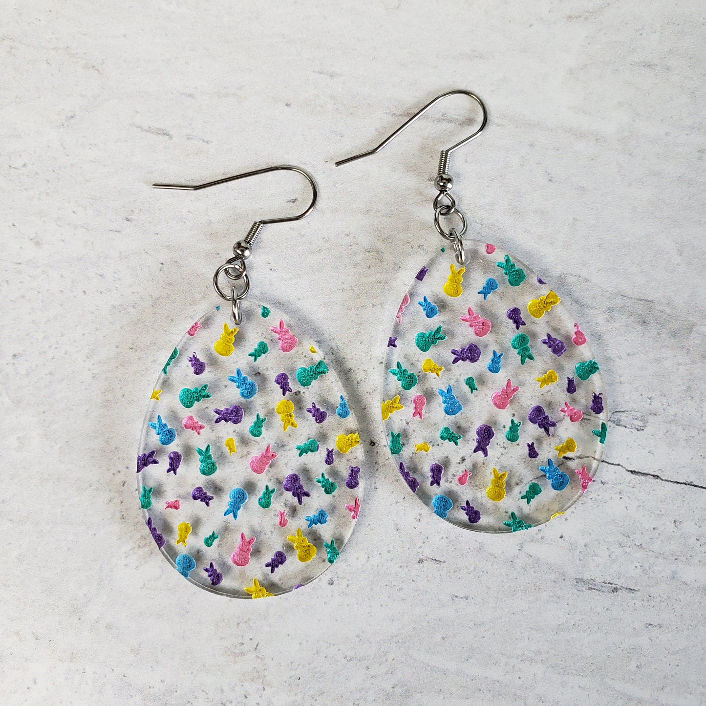 Clear egg shaped earrings with marshmallow bunnies engraved and hand painted in traditional Easter colors.