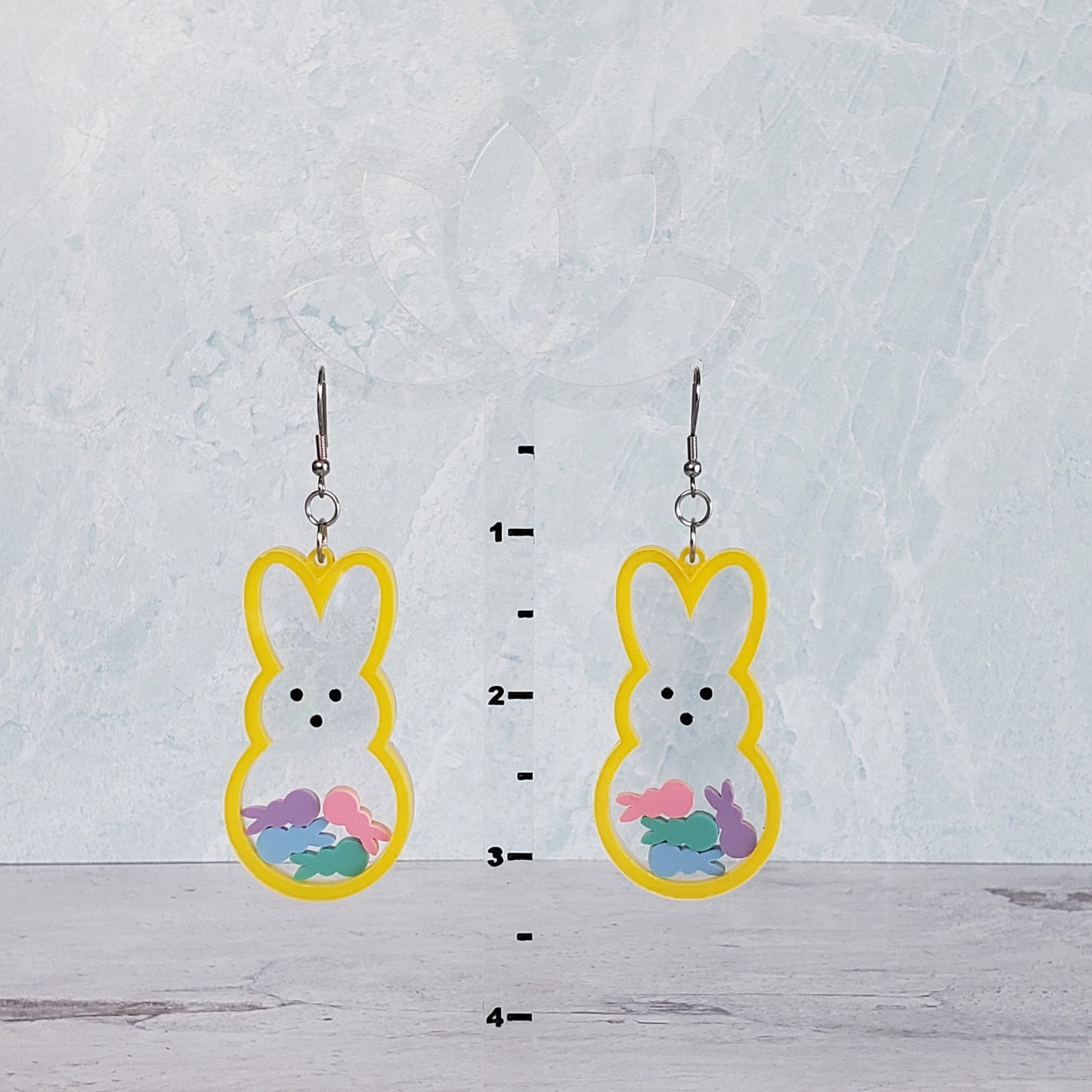 Marshmallow bunny shaker earrings in yellow with pastel bunnies inside on stainless steel earring wires on hanging display for size.