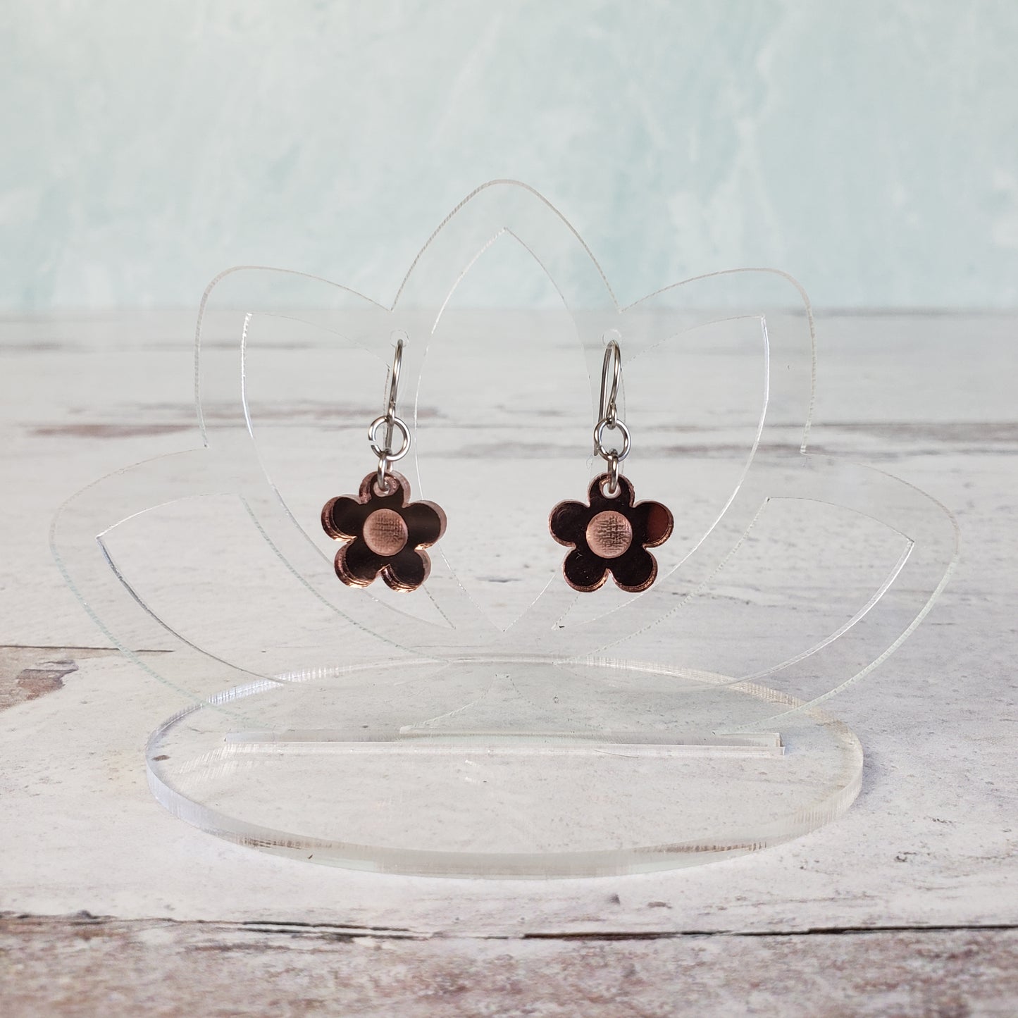 Small rose gold daisy earrings on hanging display