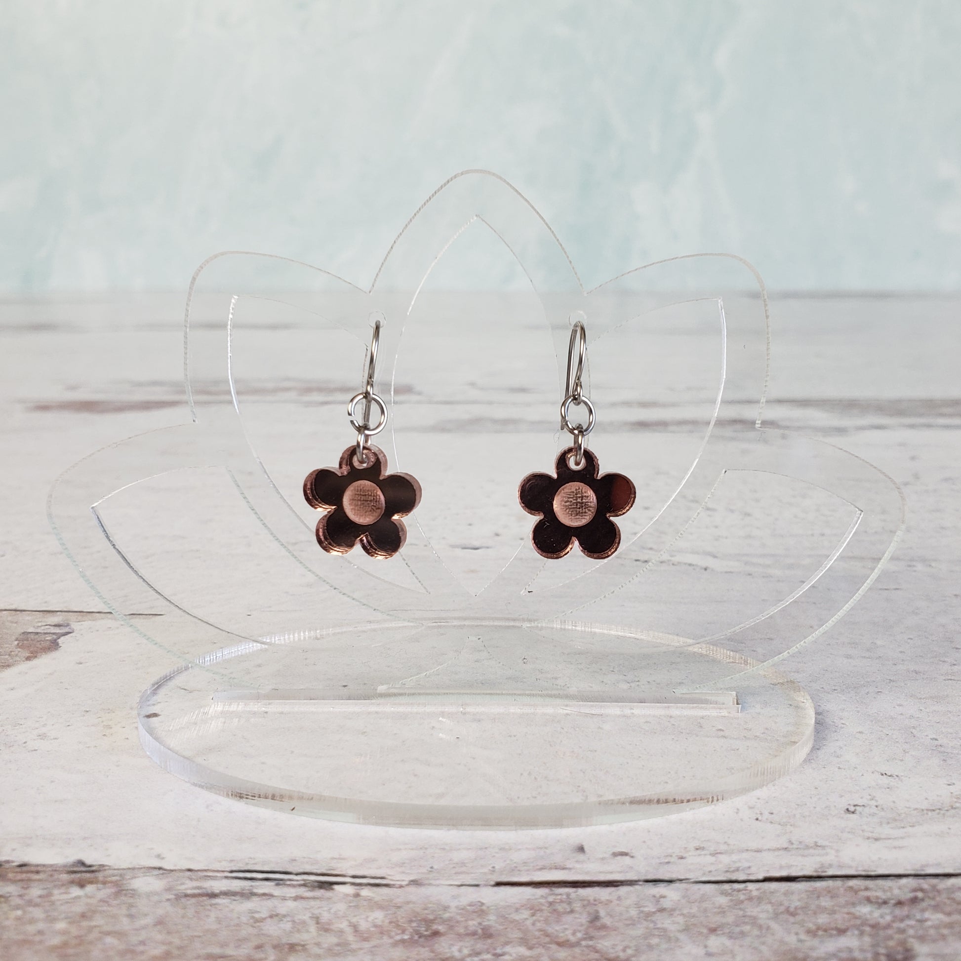 Small rose gold daisy earrings on hanging display