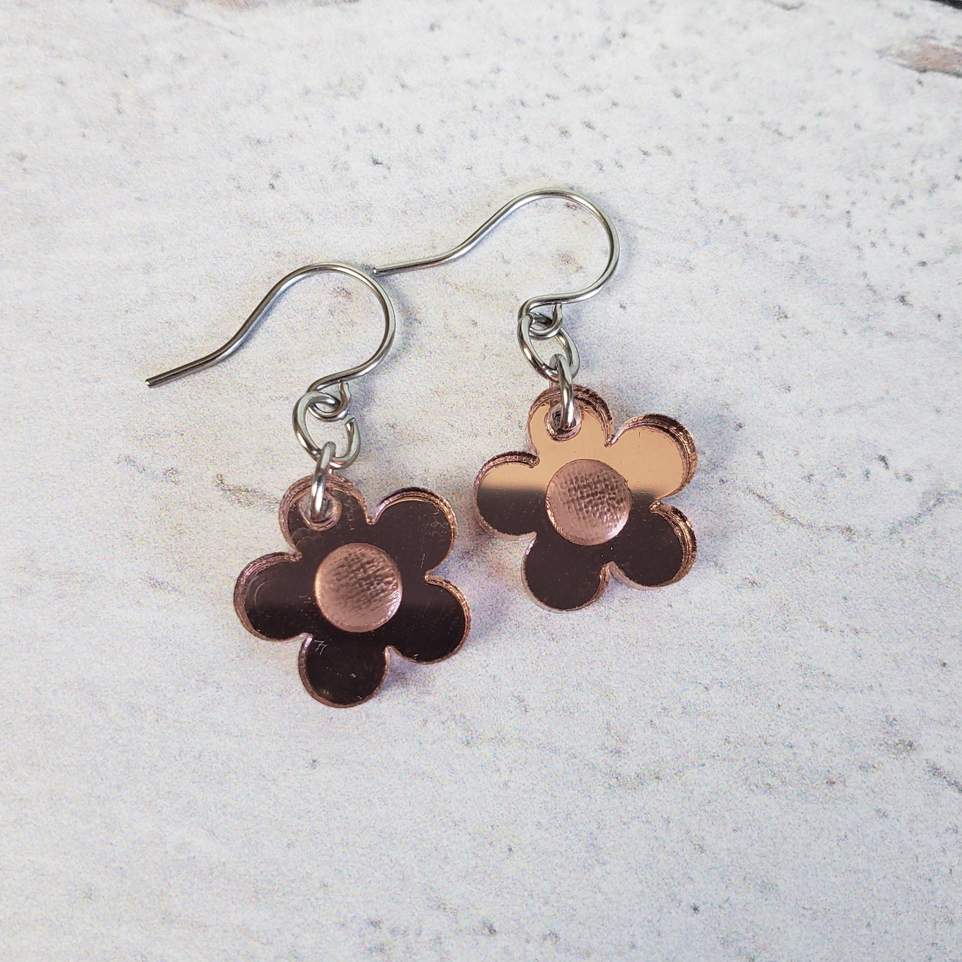 Small rose gold mirror acrylic daisy earrings on small stainless steel wires.
