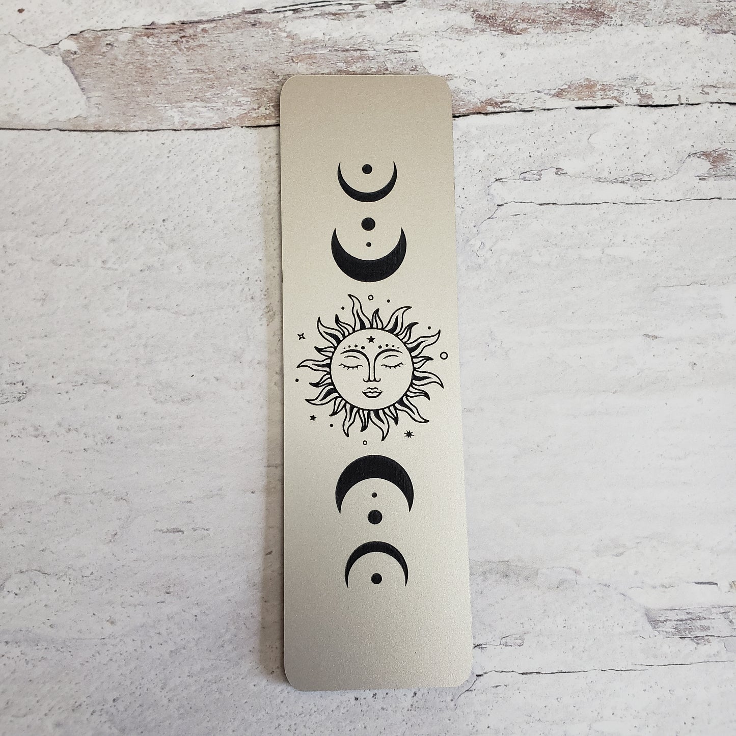 Silver tone celestial moon phase bookmark with black engraving.
