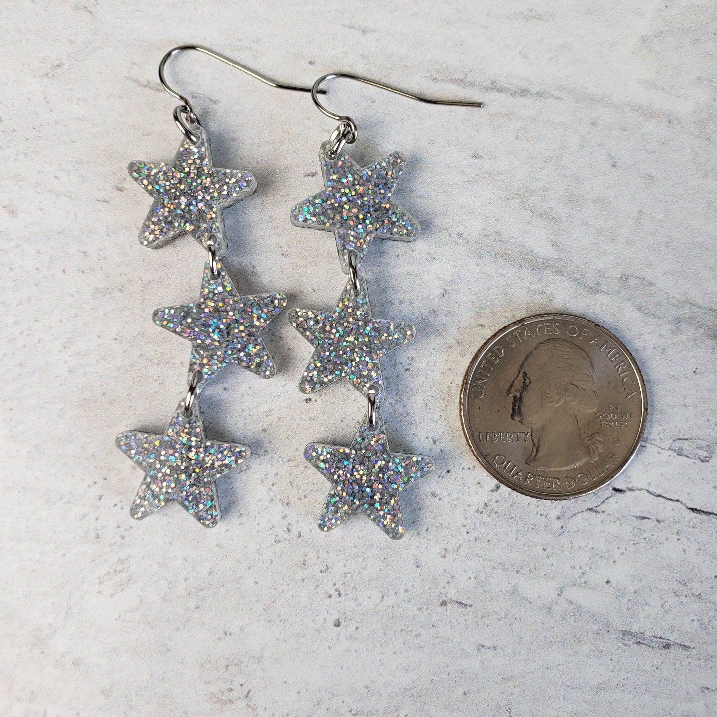 Silver holographic star dangles next to quarter for size reference