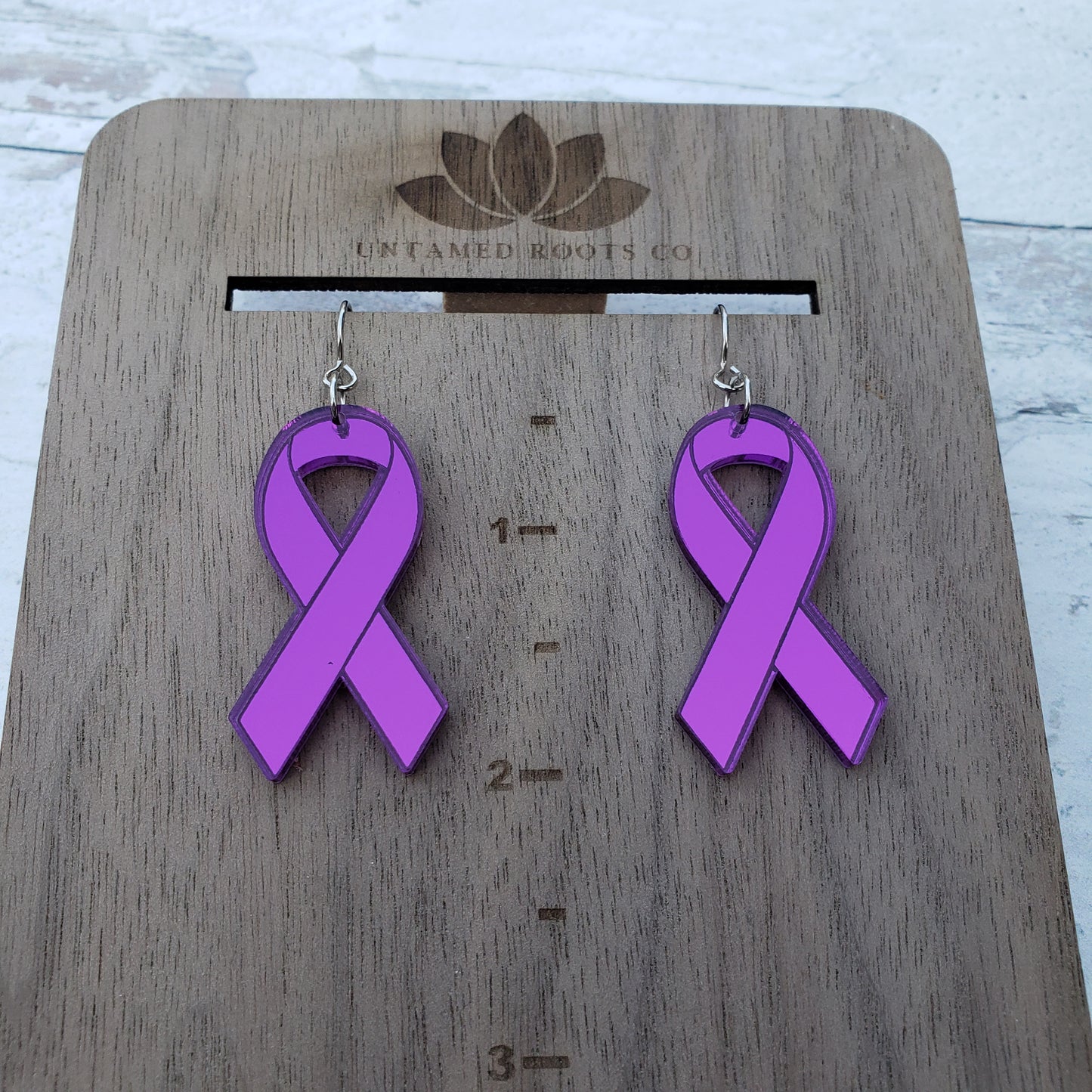 Classic purple mirror acrylic awareness ribbons on stainless steel earring wires. On hanging display for size.