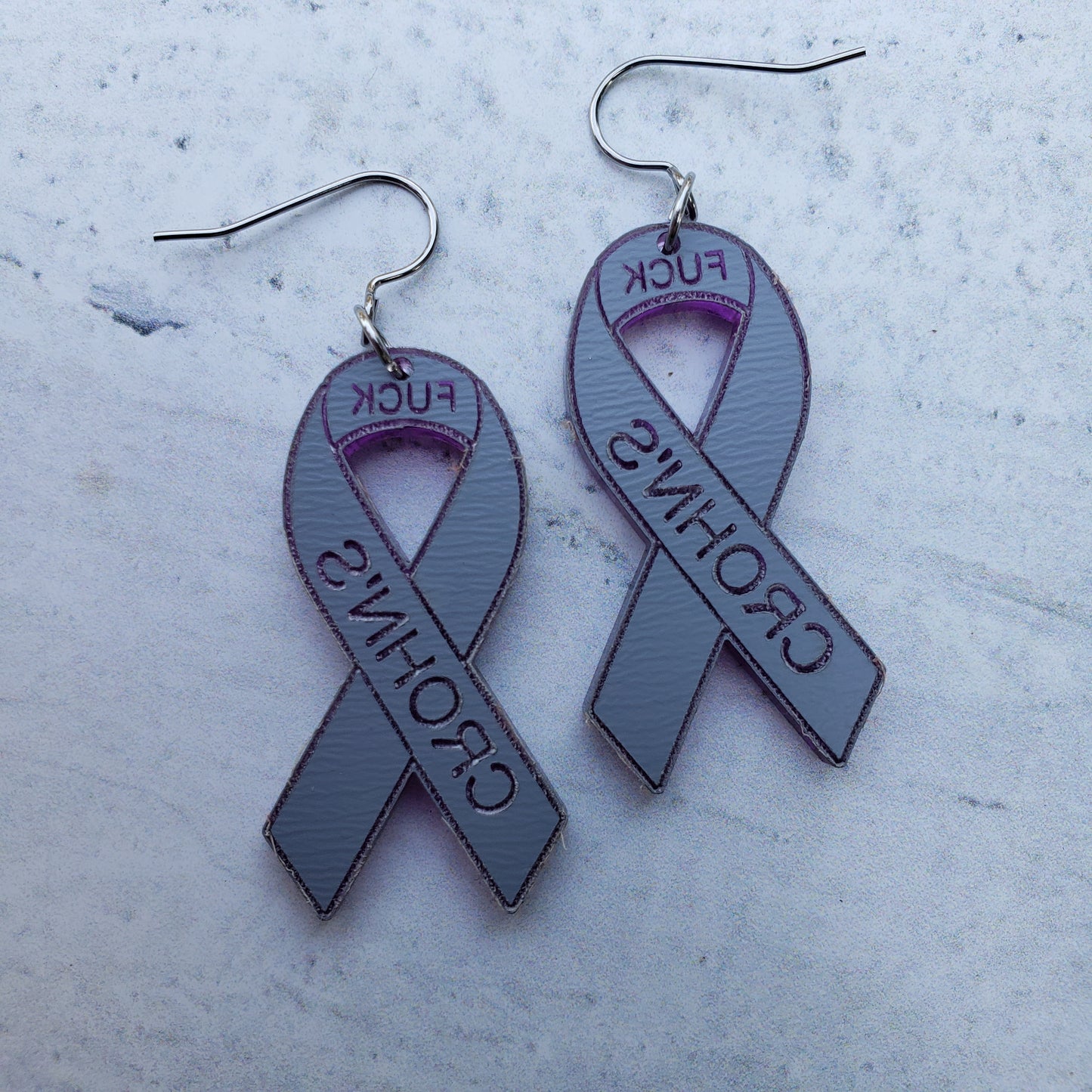 Backside of Fuck Crohn's Engraved purple mirror acrylic awareness ribbons on stainless steel earring wires.