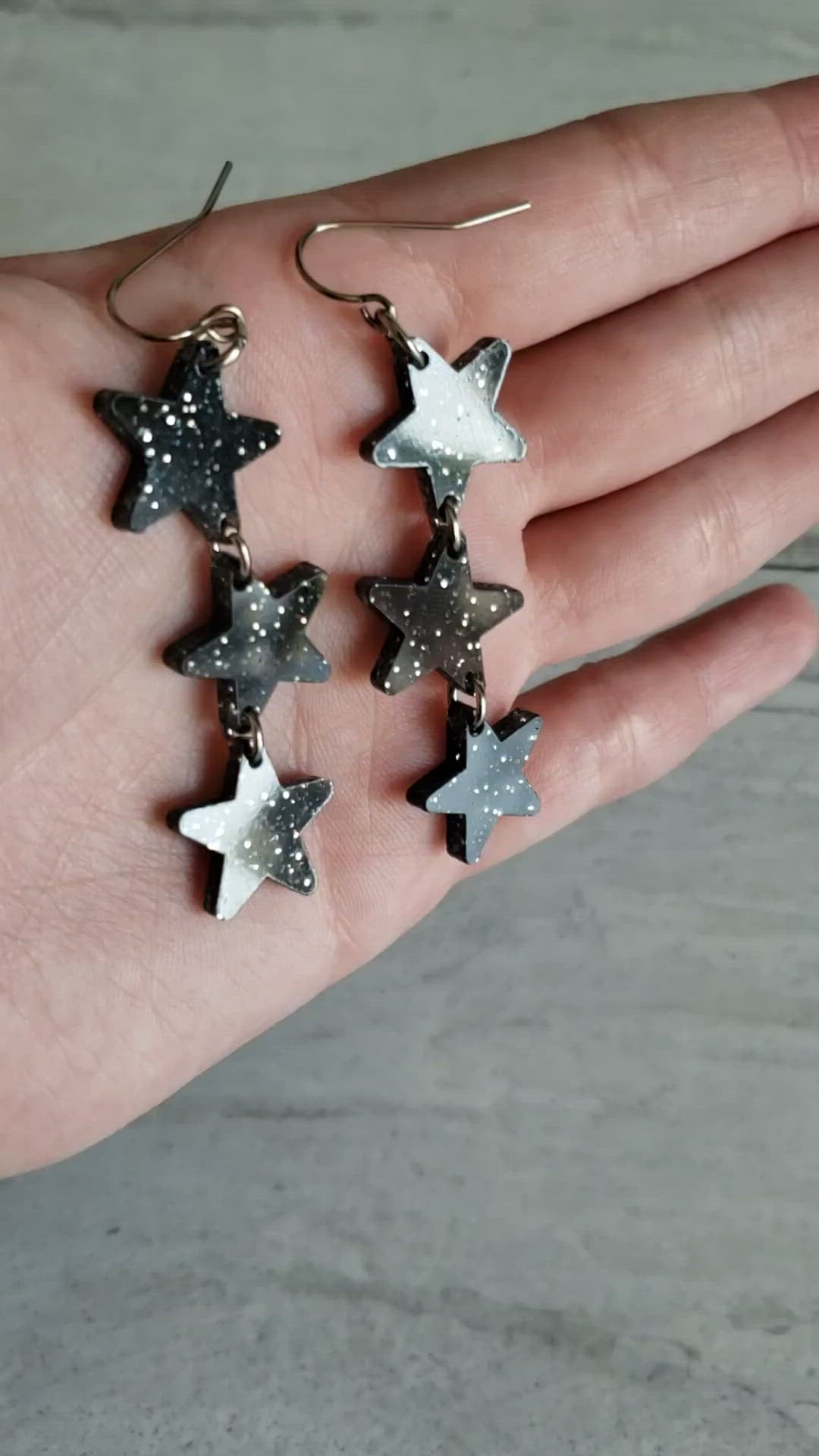 Video of black with silver glitter star dangle earrings to show effect