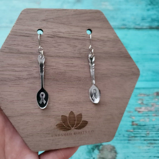 Video of silver mirror spoon shaped dangle earrings on stainless steel earring wires. Has ribbon engraving.