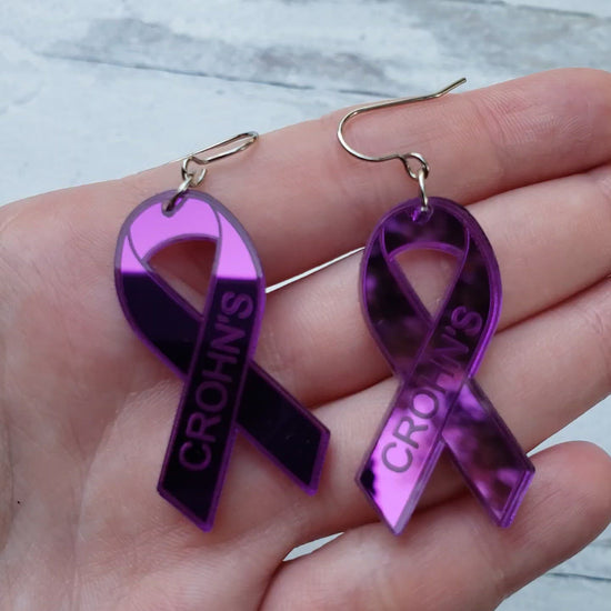 Video of Crohn's Engraved purple mirror acrylic awareness ribbons on stainless steel earring wires.