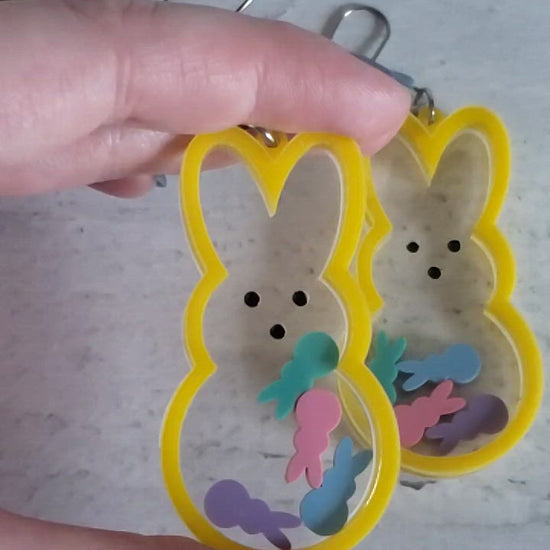 Video of Marshmallow bunny shaker earrings in yellow with pastel bunnies inside on stainless steel earring wires.