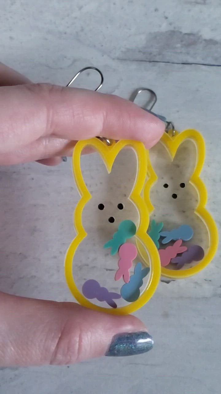 Video of Marshmallow bunny shaker earrings in yellow with pastel bunnies inside on stainless steel earring wires.