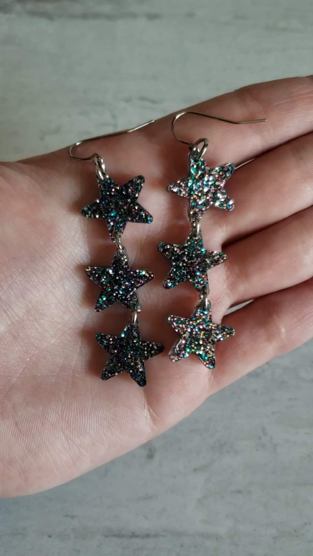 Video of dark gray galaxy holographic star dangle earrings to show effect